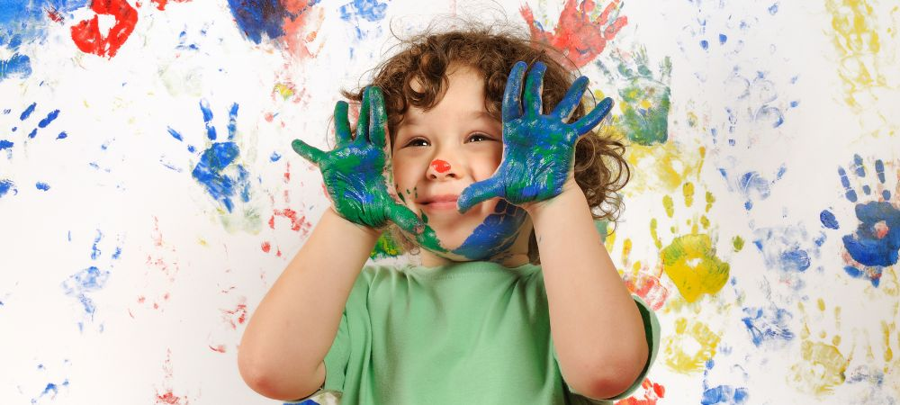 Criança com as mãos pintadas durante uma atividade artística